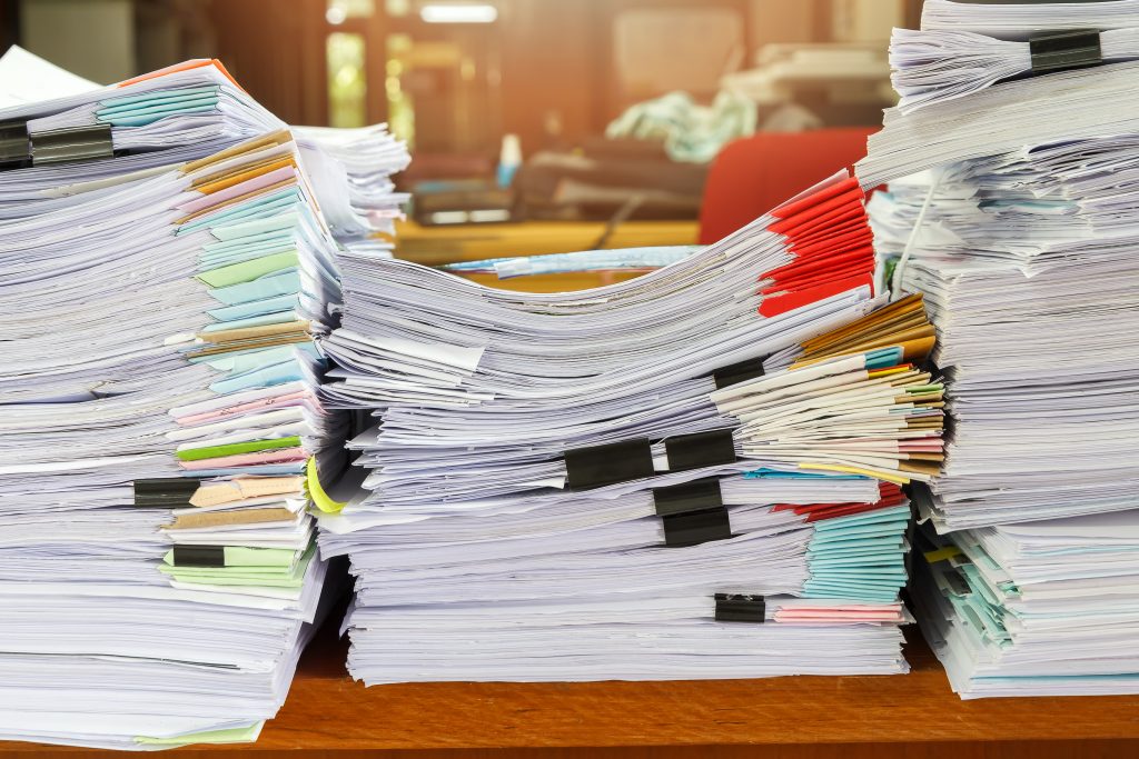 Three stacks of business documents on a desk